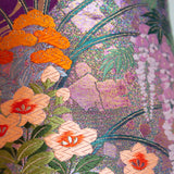 Close up of a pillow made from a vintage wedding kimono showing woven metallic threads and silk flower designs