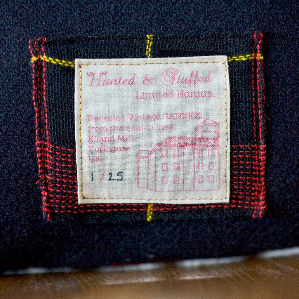 Close-up of navy wool tartan pattern highlighting the textured weave and detailed Gannex embroidery on vintage cushion