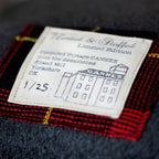 Close-up of the grey wool tartan pattern's textured weave and subtle vintage coloration on the cushion's corner detail.