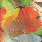 Close-up of the Obi Pillow’s silk fabric revealing intricate gold floral embroidery against vibrant red and black background