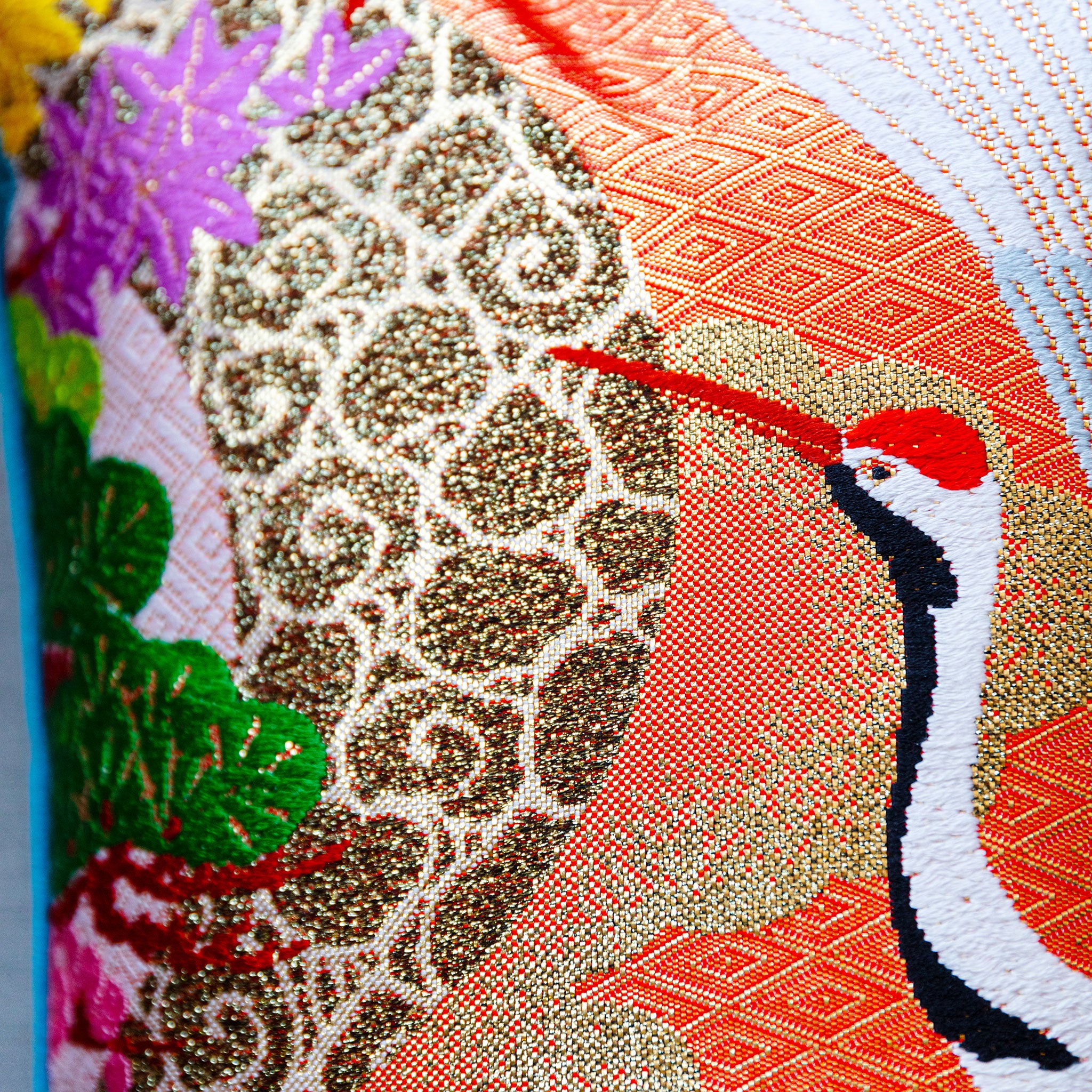 Close-up of vibrant kimono silk cranes embroidered along the pillow's blue velvet surface, highlighting intricate stitching