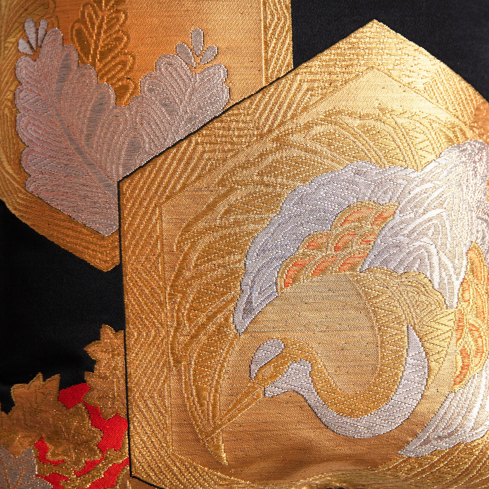 Close-up of the black silk fabric showcasing rich gold and orange embroidered floral patterns on the Obi cushion