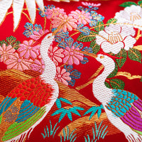 detail of a silk pillow with pair of birds and flowers over red silk base