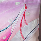 Close-up of vibrant peacock feather embroidery detail on the pink silk cushion, showcasing intricate stitching and