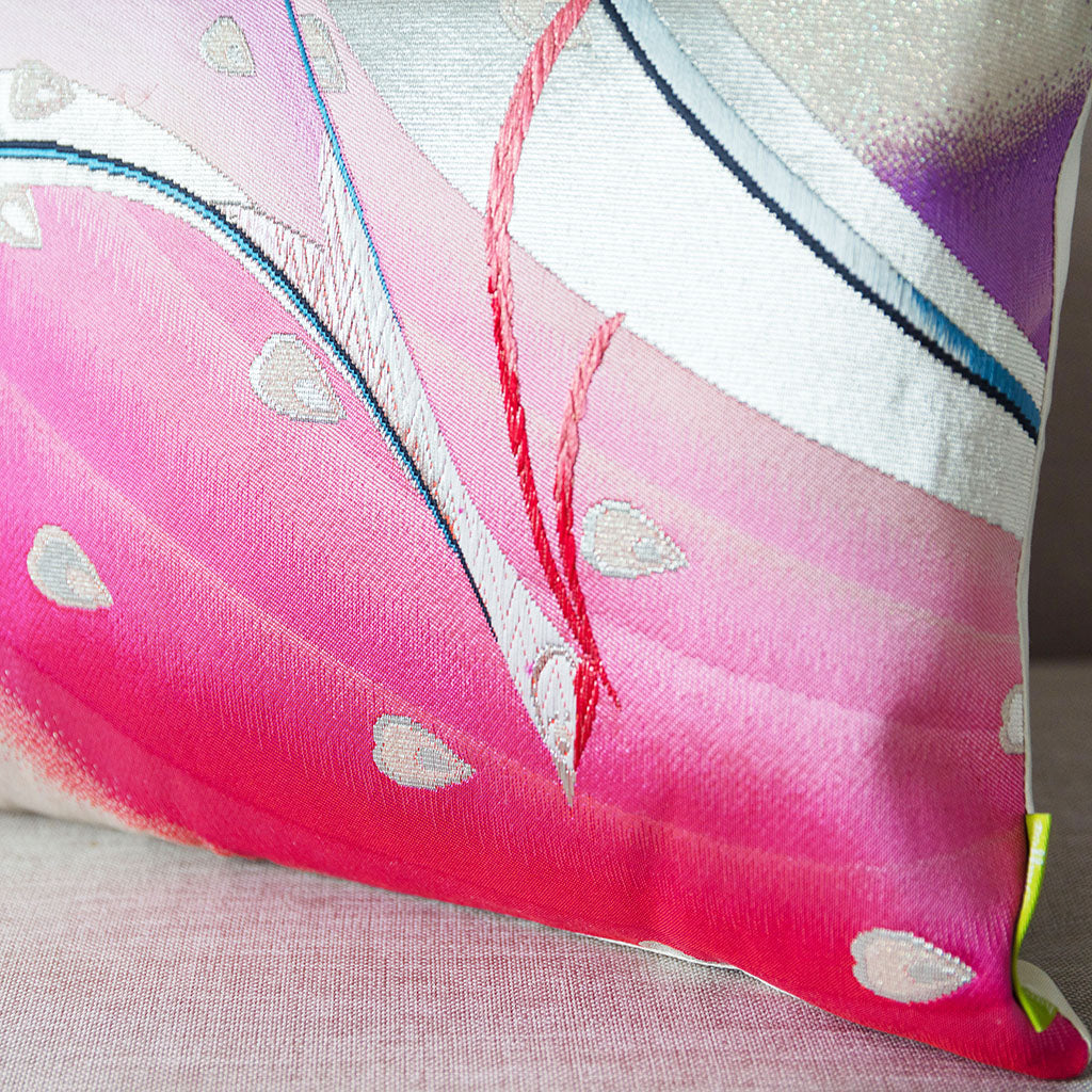 Close-up of pink silk obi fabric with intricate silver thread weaving, highlighting the detailed craftsmanship of the