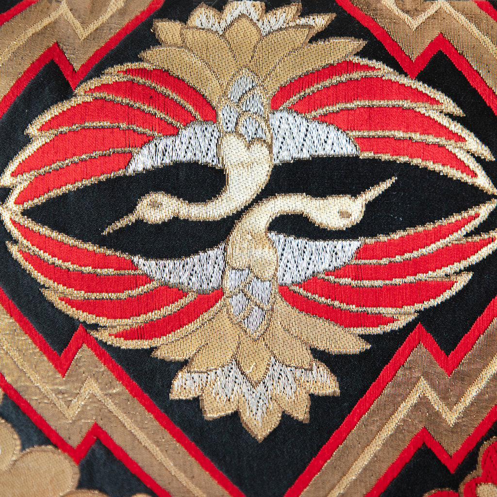 Close-up of black silk fabric highlighting intricate gold and red embroidery on the metallic obi cushion's textured surface