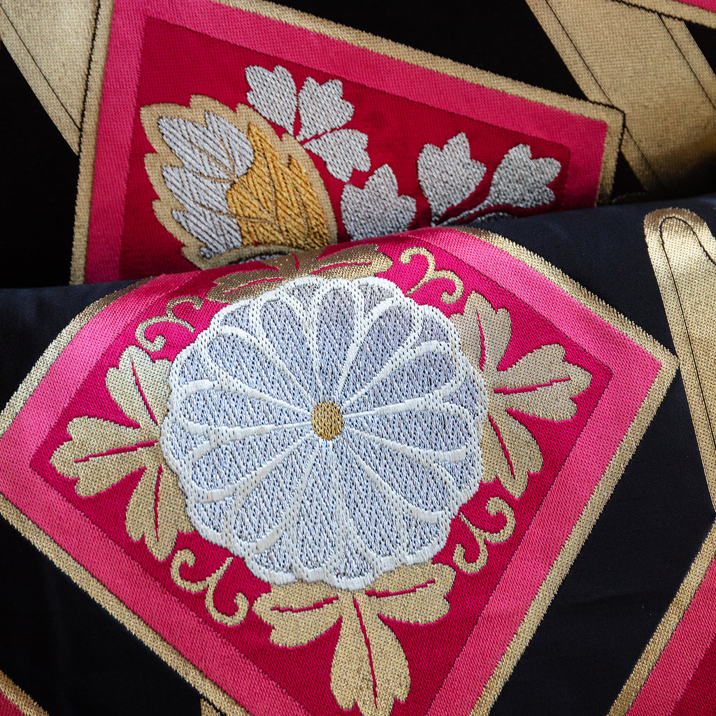 Close-up of pink silk fabric with gold accents and subtle textured weave on the pillow's corner detail