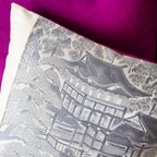 Close-up of grey silk texture with visible stitching along the cushion edge and hints of the Shocking Pink silk backing.
