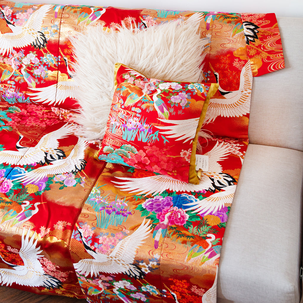 Close-up of the vibrant red silk fabric’s intricate vintage floral embroidery detail on the throw blanket's corner.