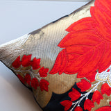 Close up of a corner of a red, gold and black silk throw pillow.