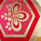 Close-up of cream silk obi pillow fabric showing vibrant red hexagon Kiri flower pattern and intricate embroidered details