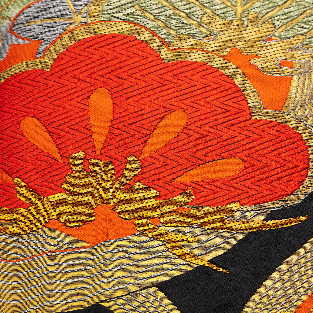 Close-up of red gold pine tree embroidery detail on black velvet cushion showing intricate stitching and textured fabric