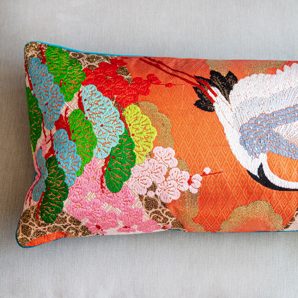 Close-up of vibrant kimono silk cranes embroidered on the blue velvet bolster pillow's curved corner detail