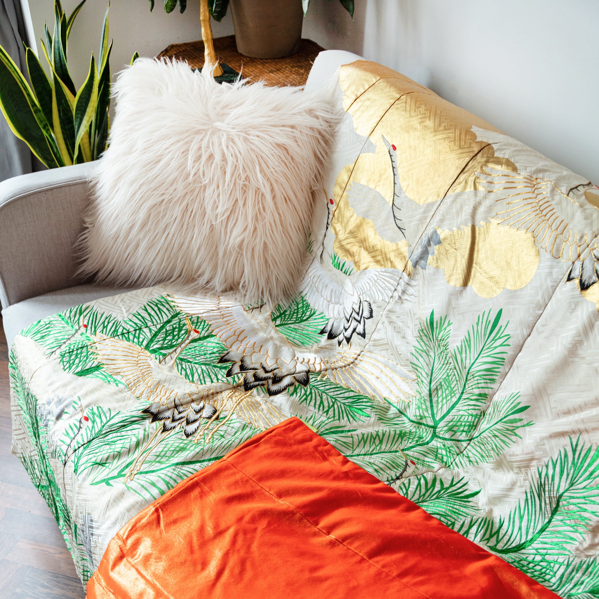 Close-up of intricate silk crane embroidery detailing the vintage floral pattern on the throw blanket fabric corner.