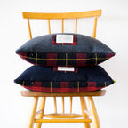Close-up of textured grey wool tartan fabric showing intricate plaid pattern and vintage upcycled details on the cushion