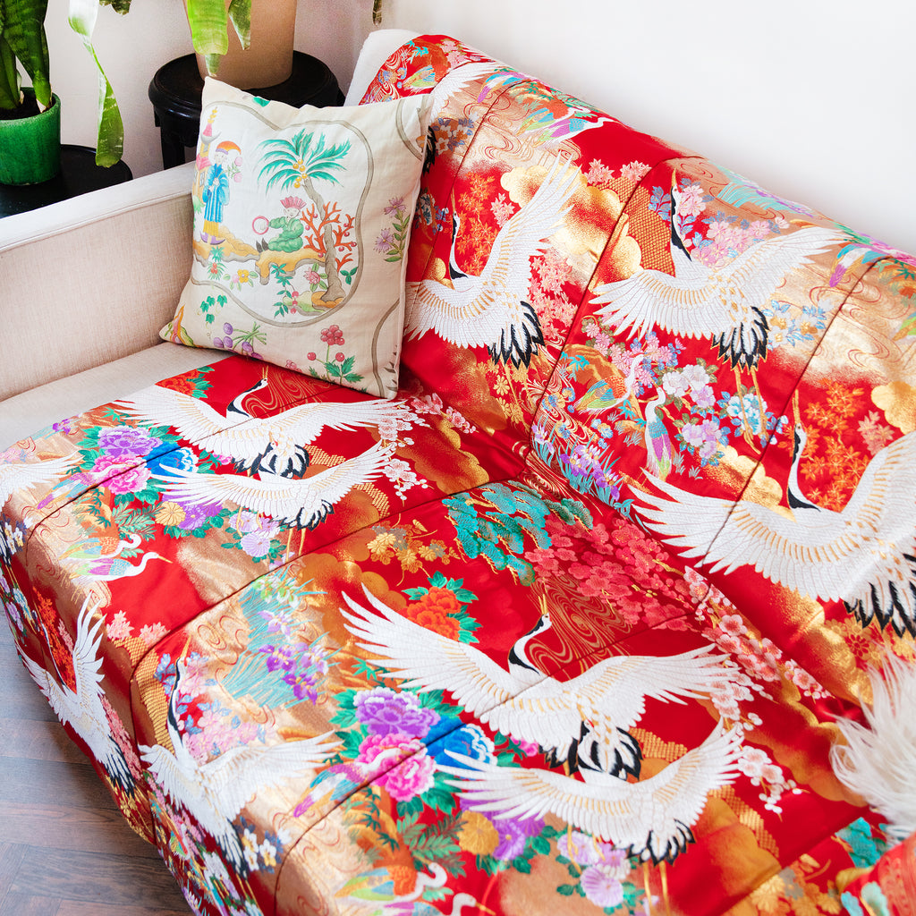 Close-up of the rich red silk fabric’s intricate vintage floral embroidery along the blanket edge