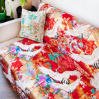 Close-up of the rich red silk fabric’s intricate vintage floral embroidery along the blanket edge