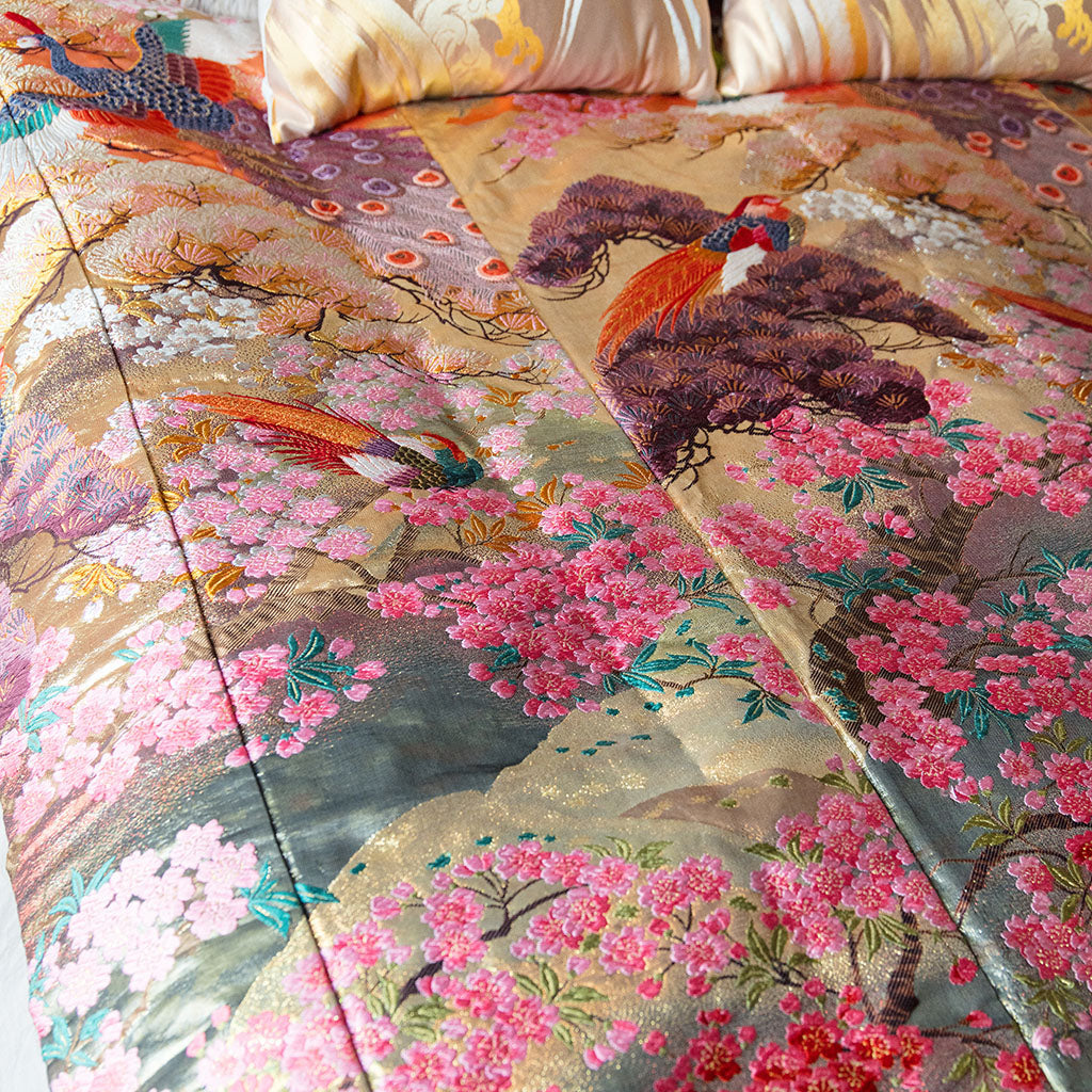 Close-up of vintage kimono-inspired silk throw blanket’s intricate floral embroidery and rich jewel-tone colors from a