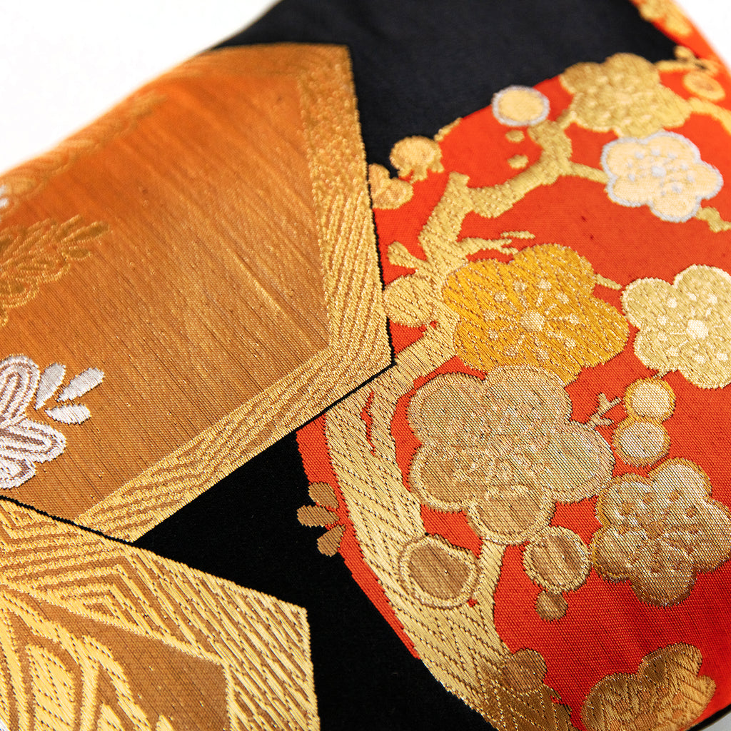 Close-up of the black silk fabric featuring intricate gold and orange Chinoiserie patterns, highlighting detailed embroidery