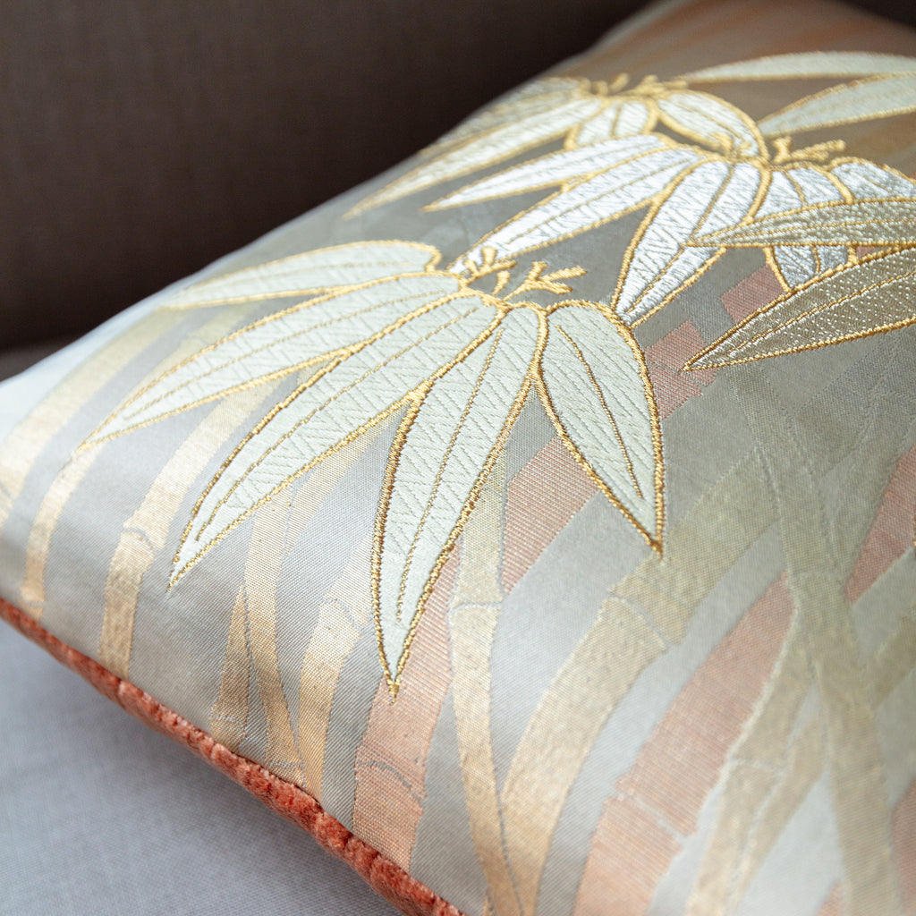 Close-up of the vintage gold bamboo detailing on the pillow's peach velvet back, highlighting intricate craftsmanship and