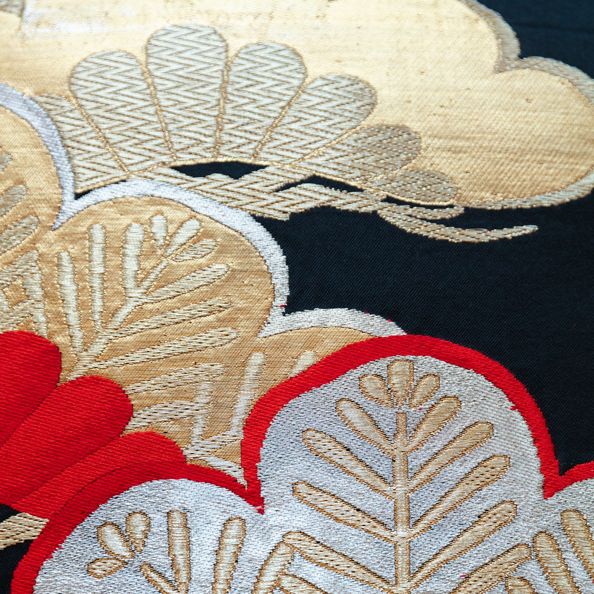 Close-up of gold velvet pine pattern embellishing the black silk obi pillow surface, highlighting intricate textile details