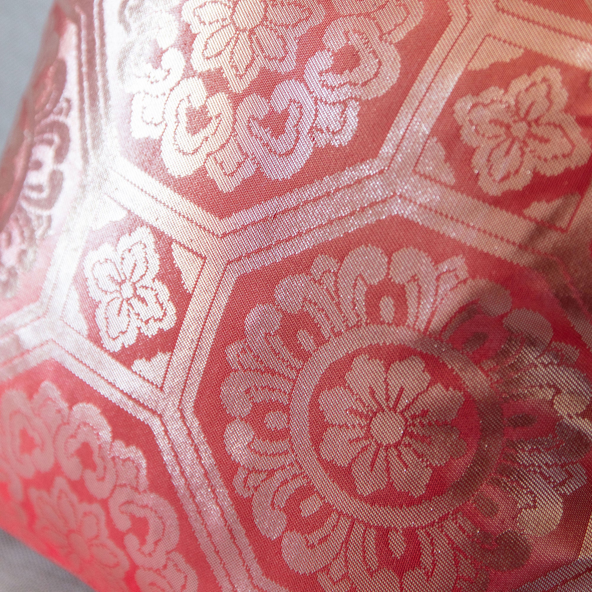 Close-up of the pink silk fabric highlighting silver geometric embroidery detail on the 1930s Obi cushion’s 12-inch textile