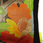 Close-up of black silk fabric showcasing red, yellow, and gold embroidered flower details on the Floral Obi Cushion.