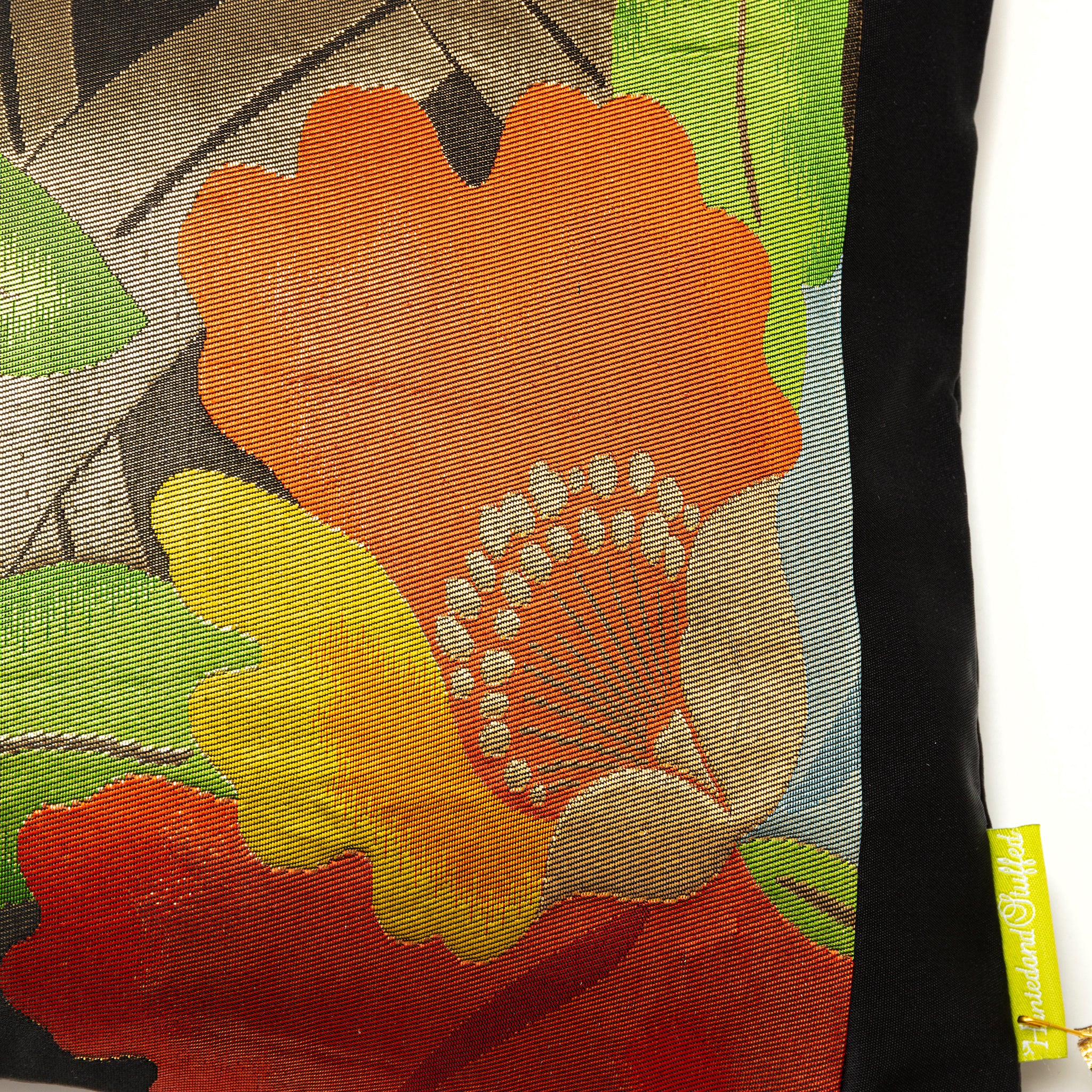 Close-up of black silk fabric showcasing red, yellow, and gold embroidered flower details on the Floral Obi Cushion.