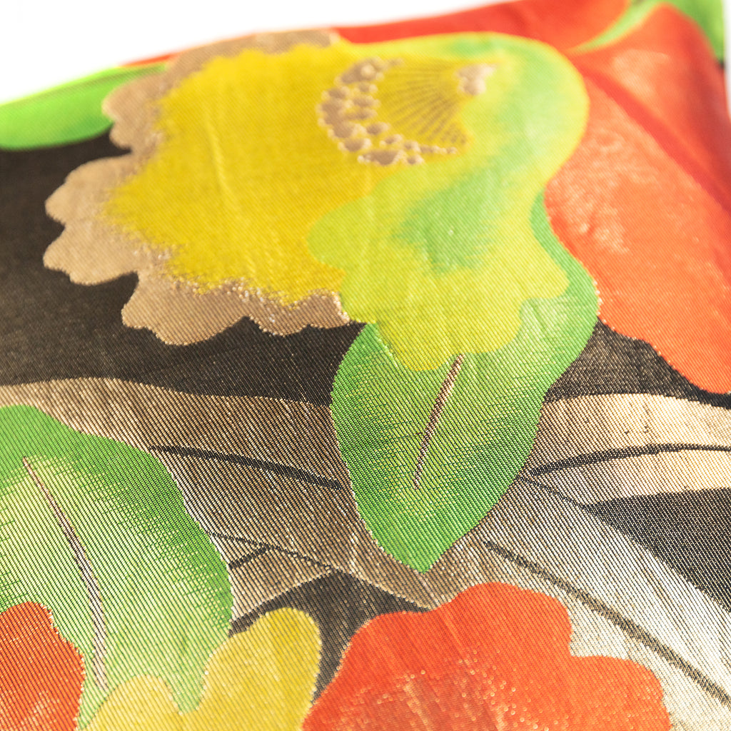 Close-up of textured silk fabric showcasing intricate gold and black floral details on the red background of Obi Pillow #5.